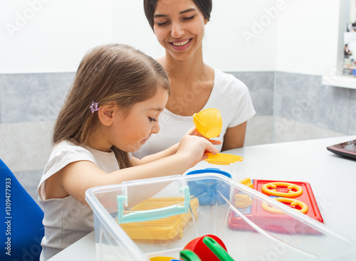 Child engages in a playful activity with a therapist, enhancing fine motor skills and cognitive abilities through colorful toys in a therapy setting