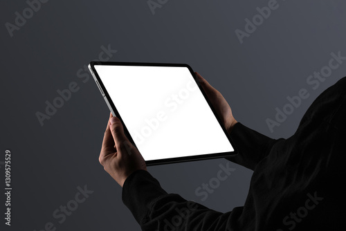 A person dressed in black holding a tablet in landscape orientation. Isolated blank mockup surface to place your design. 