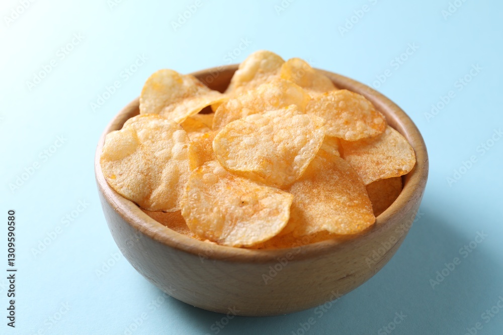 Tasty potato chips in bowl on light blue background, closeup Tasty potato chips in bowl on light blue background, closeup