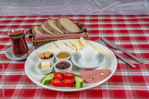 Traditional Turkish breakfast plate. The plate contains cheese varieties, jam, honey, eggs, tomatoes, cucumber, butter, olives and salami.