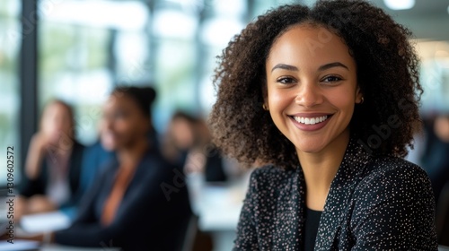 A Smiling Woman with Curly Hair and Meeting Attendees