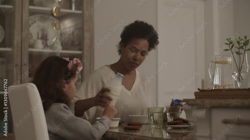 Happy woman and girl having breakfast at table Happy woman and girl having breakfast at table