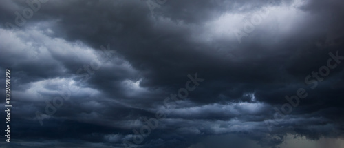 A dense, dark sky filled with swirling storm clouds signals an intense windstorm, emphasizing the power and drama of nature's environment in turbulent weather conditions.