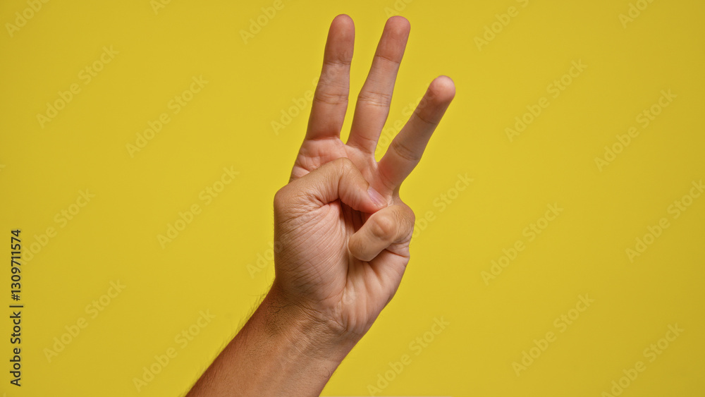 Naklejka premium Man holding up three fingers against a bright yellow background