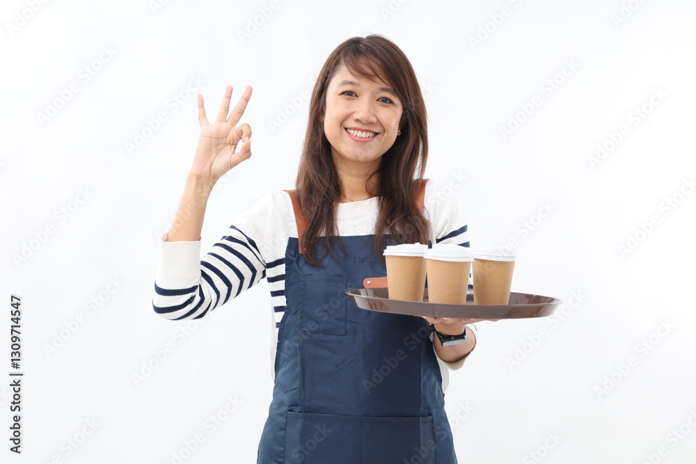 Happy asian barista wear apron showing okay sign while holding coffee paper cups on a tray Happy asian barista wear apron showing okay sign while holding coffee paper cups on a tray