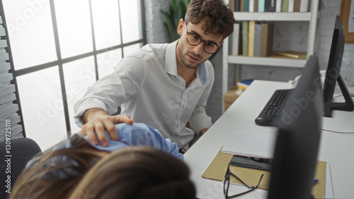 Man comforting woman in modern office setting, suggesting teamwork and support among colleagues indoors, showcasing employee dynamics in a corporate environment.