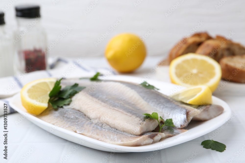 Marinated herring fillets with lemon and parsley on white tiled table, closeup Marinated herring fillets with lemon and parsley on white tiled table, closeup