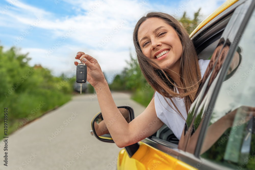 A cheerful woman in a white sleeveless shirt holds car keys while leaning out of the window of a yellow car on a sunny day, surrounded by a scenic countryside road.