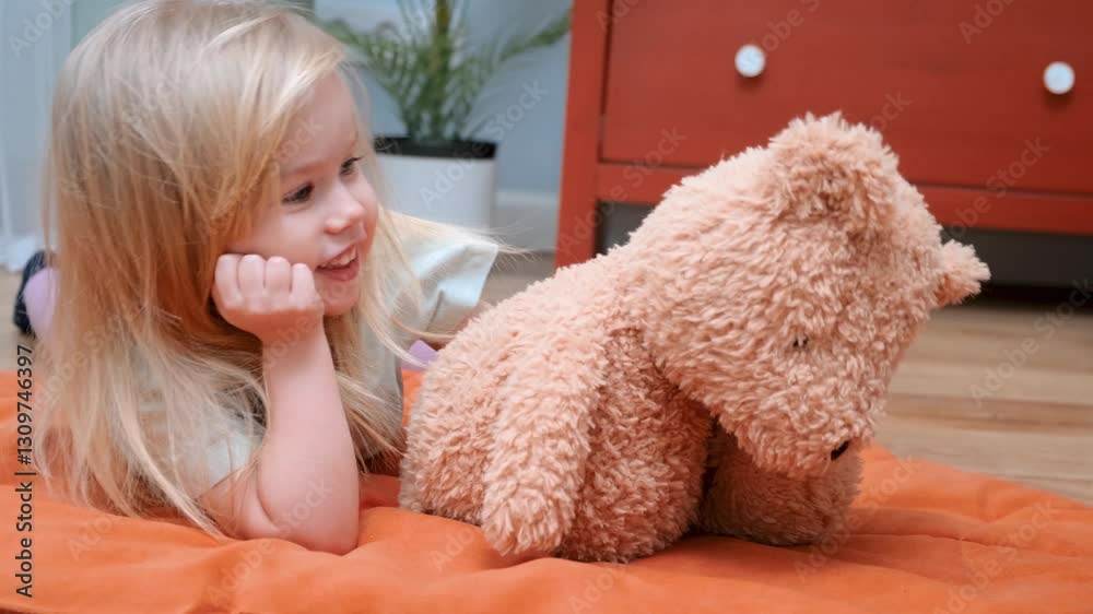 Smiling caucasian child girl hugs a bear toy AT home Smiling caucasian child girl hugs a bear toy AT home