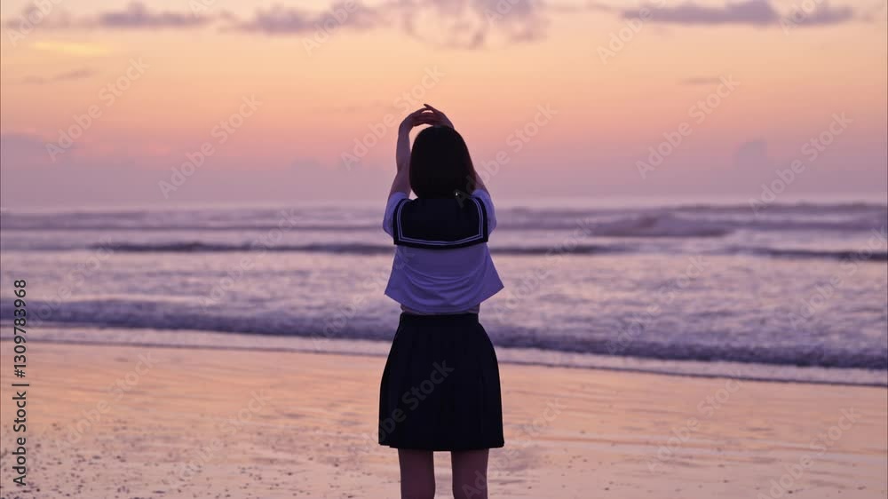 朝焼けの海岸で背伸びをする女子高校生