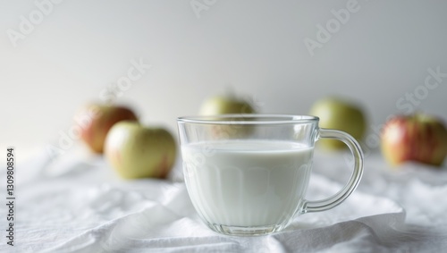 Glass Mug of Milk with Apples in Background.