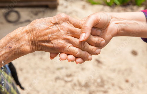 Hand einer alten Frau in der Hand einer jungen Frau