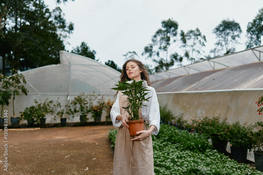 Φωτογραφία Young woman holding a potted plant in a botanical garden, showcasing joy and con