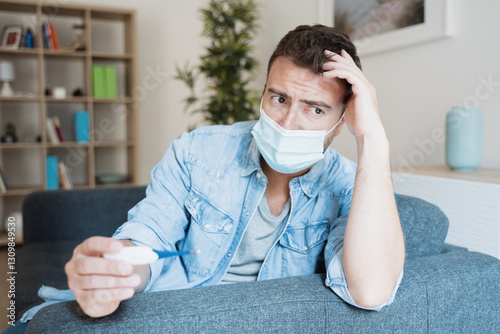 Man wearing face mask and checking body temperature