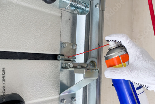 A worker lubricates sectional doors after installation in a garage.
