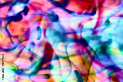 Abstract video with vibrant colors flowing with colored inks dispersed in water. The composition consists of shades of blue, red, green and yellow blending and swirling on a light background, creating
