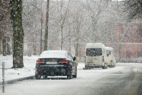 Cars parked on the side of the road in the city during a snowfall in winter
