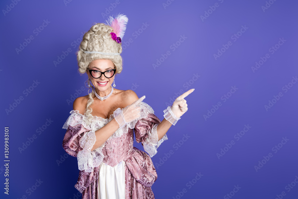 Fototapeta premium Elegant woman dressed in historical style, pointing with both hands on a purple background, portraying a regal and humorous character.