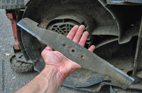 lawn mower knife in a man's hand. replacing a lawn mower blade