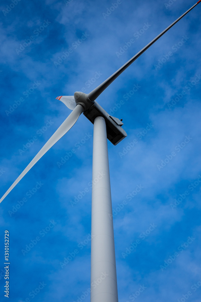 White wind turbine rotor against a blue sky background. Electric generator photographed from below