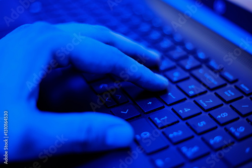 Close-Up of a Hand Typing on a Keyboard in Dim Blue Light