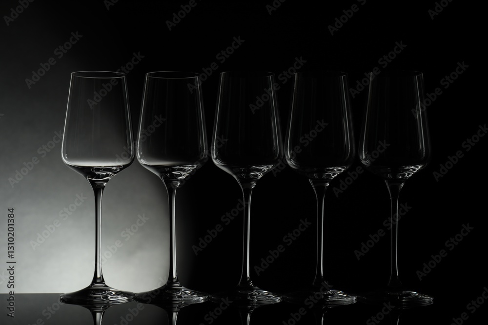 Many empty clean glasses on mirror surface against black background Many empty clean glasses on mirror surface against black background