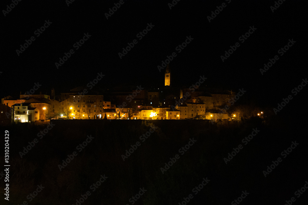 Fototapeta premium Night shot of the illuminated old town on the hill, colorful lights