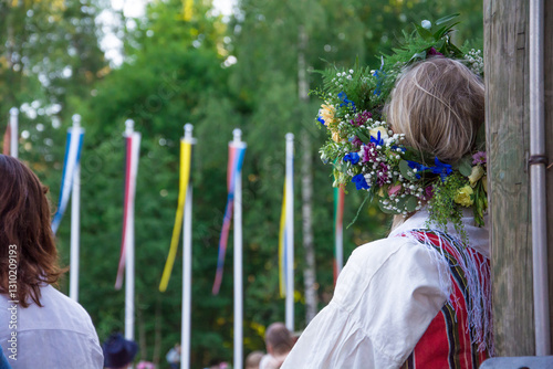 A woman in a Finnish national costume looking into the distance during midsummer festival celebration