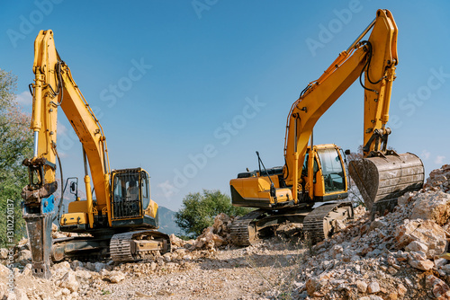 Two Yellow Excavators on Construction Site with Rocky Terrain