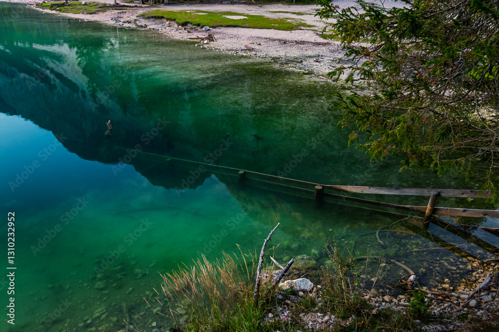 lago di braies, pragser Wildsee lake, at the morning in summer stones with a fence in the water