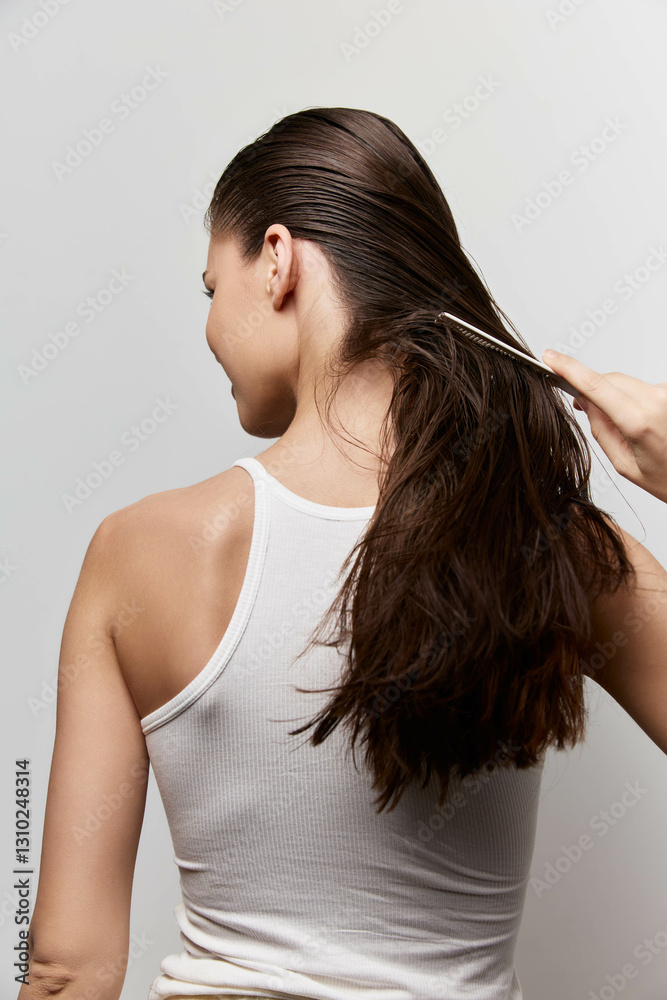 Hair care, beauty routine, healthy hair, woman caring for hair, back view, white background, smooth hair, styling concept A young woman is seen combing her wet hair, showcasing a beauty routine Hair care, beauty routine, healthy hair, woman caring for hair, back view, white background, smooth hair, styling concept A young woman is seen combing her wet hair, showcasing a beauty routine