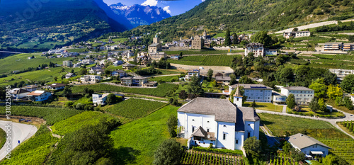 Switzerland travel, scenic places in Valais canton. Leuk town surrounded by vineyards and Alps mountains. Aerial drone panorama with medieval castles and village
