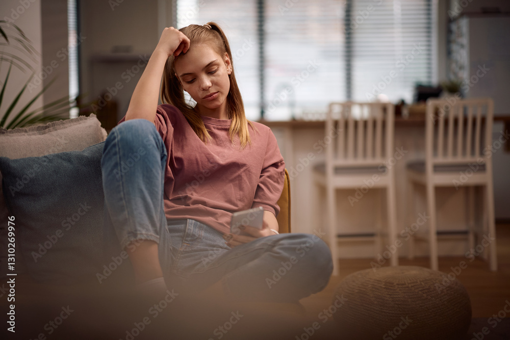 Displeased teenage girl reading text message on mobile phone at home. Displeased teenage girl reading text message on mobile phone at home.
