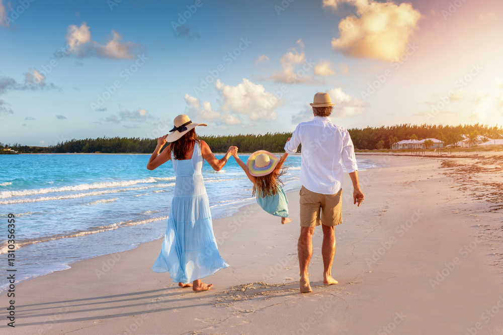 A happy family in walks hand in hand down a tropical beach during sunset tme and enjoys their summer vacation time