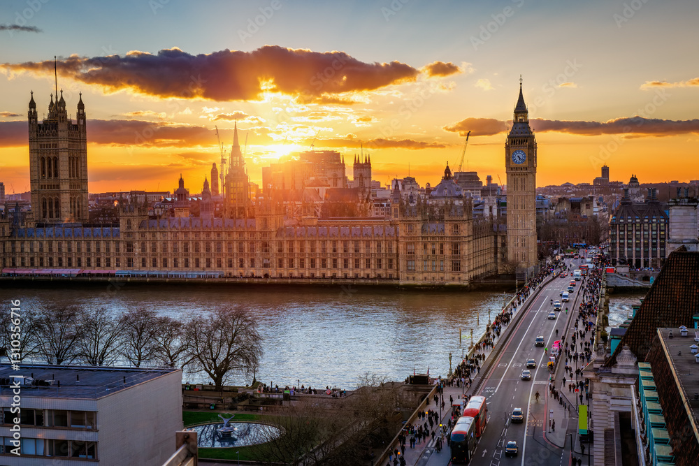 Golden sunset view of the Westminster Palace and famous Big Ben clock tower in London with street and people traffic, England