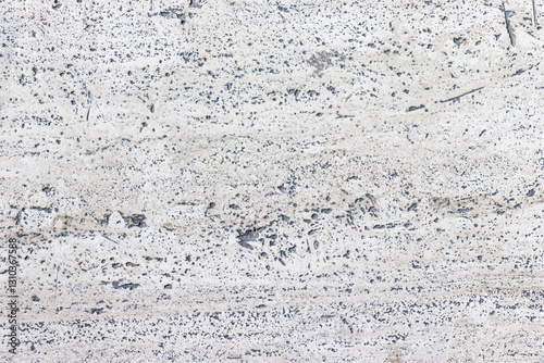 Straight down view of a large slab of light porous stone floor.