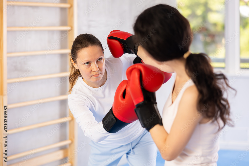 Adult woman and young woman training boxing punches in studio Adult woman and young woman training boxing punches in studio