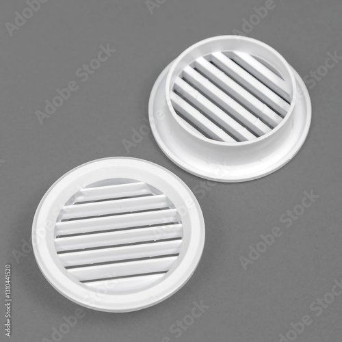 White ventilation grate on a gray background. Round shape. An element of the ventilation system.