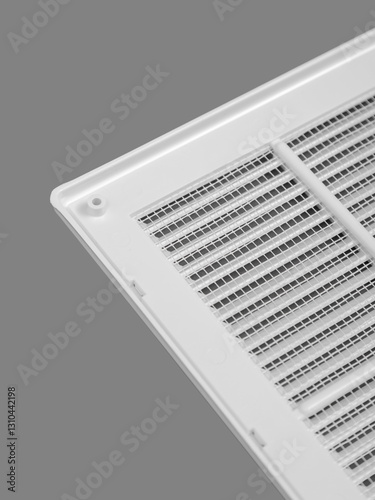 White ventilation grate on a gray background. Close-up. Material is plastic. Back side with mesh.
