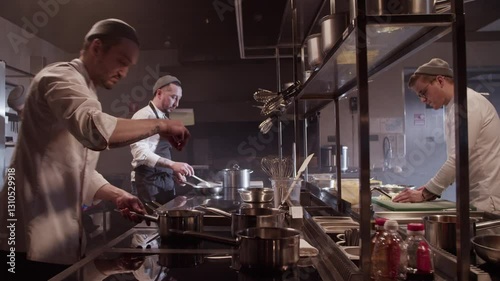 Male cooks working at kitchen counter and preparing food