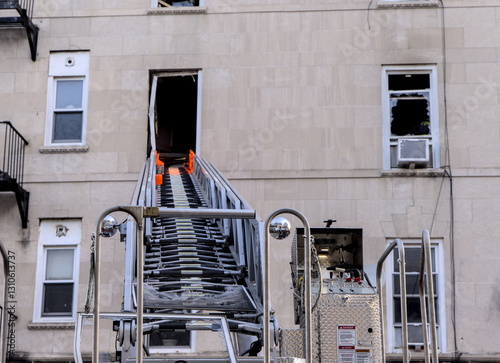 FDNY fire trucks responding to an apartment fire on Bedford Avenue in Brooklyn New York City with ladders into broken windows.