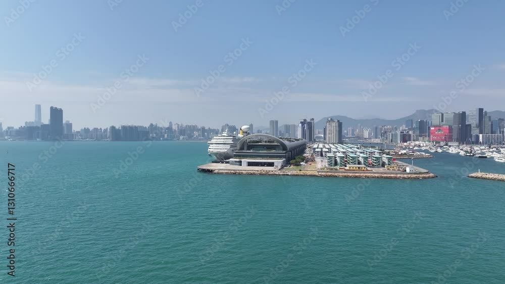 Drone aerial skyview of a mega luxury cruise ship sailing at the Kai Tak cruise terminal, showcasing the vibrant Victoria Harbour and the iconic city skyline of Kwun Tong Kowloon Hong Kong Drone aerial skyview of a mega luxury cruise ship sailing at the Kai Tak cruise terminal, showcasing the vibrant Victoria Harbour and the iconic city skyline of Kwun Tong Kowloon Hong Kong