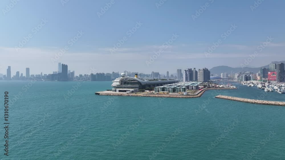 Drone aerial skyview of a mega luxury cruise ship sailing at the Kai Tak cruise terminal, showcasing the vibrant Victoria Harbour and the iconic city skyline of Kwun Tong Kowloon Hong Kong Drone aerial skyview of a mega luxury cruise ship sailing at the Kai Tak cruise terminal, showcasing the vibrant Victoria Harbour and the iconic city skyline of Kwun Tong Kowloon Hong Kong