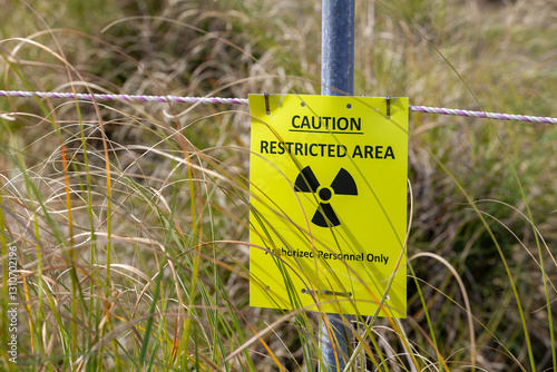 Caution restricted area radiation warning sign in a grassy outdoor environment indicating a hazardous zone