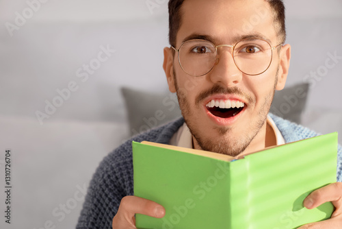 Happy young man reading boo...