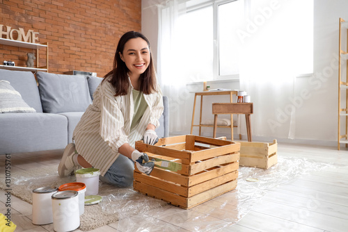 Young woman painting wooden...