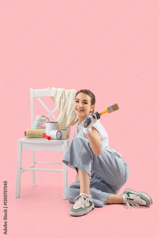 Young woman with brush and cans painting chair on pink background Young woman with brush and cans painting chair on pink background