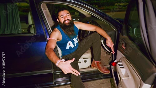 Bearded man grooves inside a car one leg outside