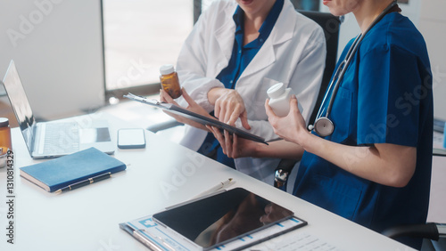 Two Caucasian female doctors work at a desk, meeting and discussing patient treatment while using a medical program modern technology in a hospital to ensure effective healthcare medicine management