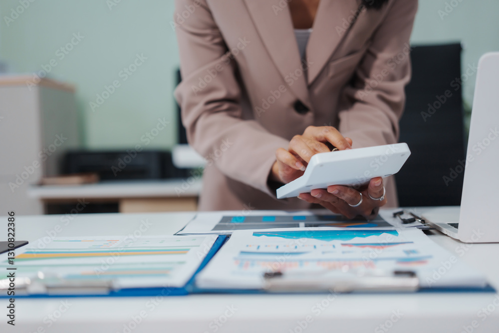Fototapeta premium An Asian businesswoman accountant calculates invoices, taxes, interest, loans using a calculator,working online to guide clients through financial planning ensure a smooth loan process for success